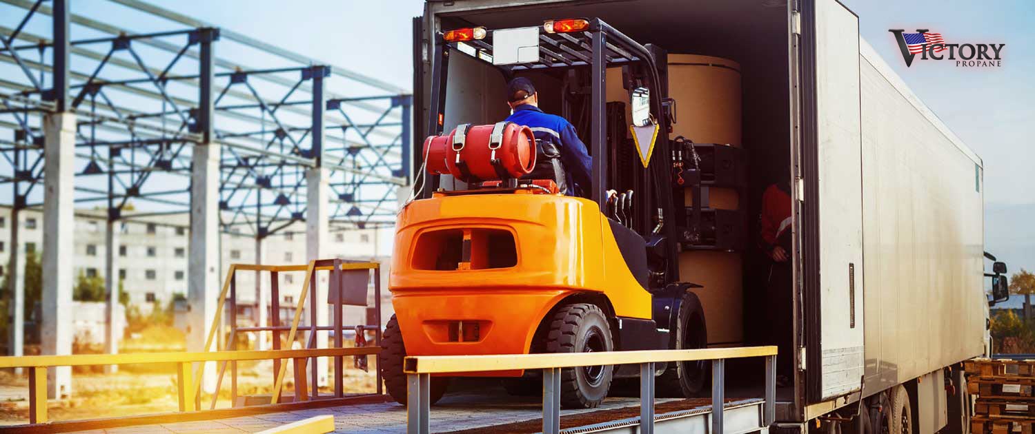 orange forklift pulling item from the back of a truck