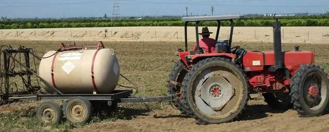 red tractor pulling a tank on a trailer
